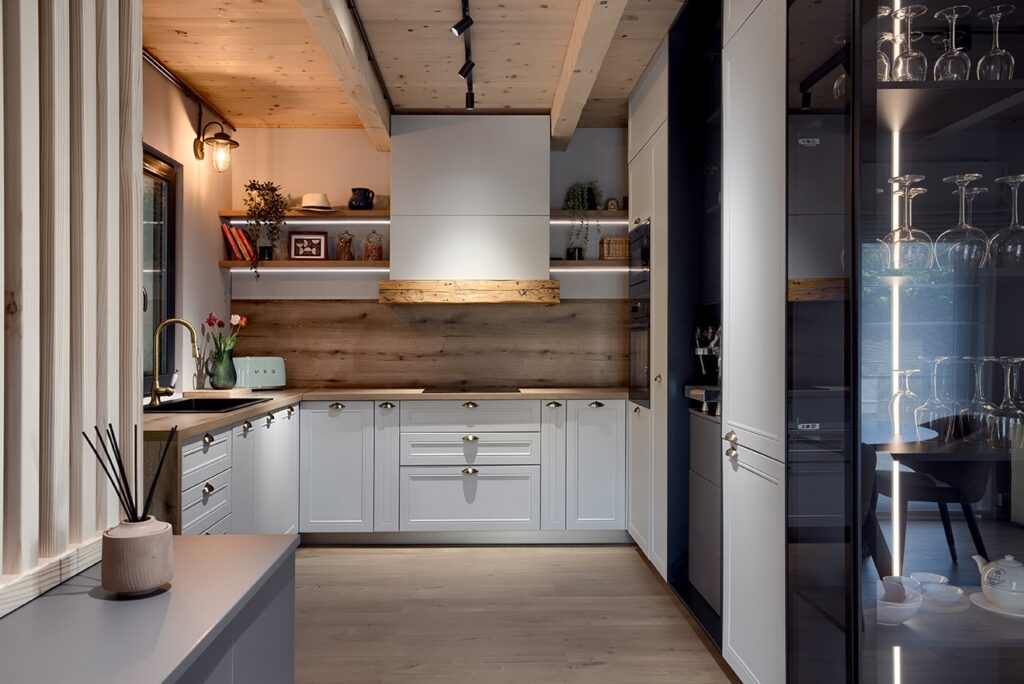 Contemporary Scandinavian-inspired kitchen design, featuring recessed spotlights, minimalist white cabinetry with classic brass knobs, and warm wood finishes, track lighting.