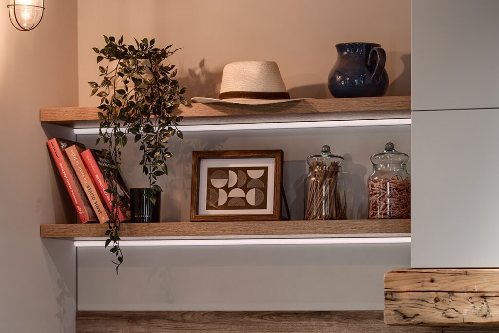 Stylish wall-mounted wooden shelves with under-shelf led lighting, featuring a mix of decorative and functional items in a warm, modern kitchen setting.