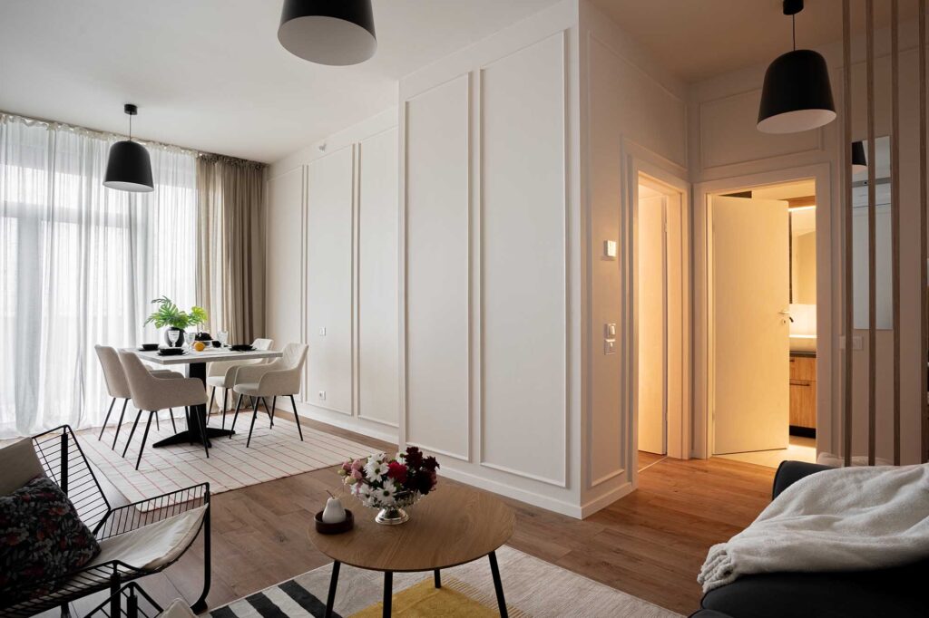 Inviting hospitality apartment captured by professional interior photographer Sergiu Ilisie in soft daylight, featuring a modern dining area with neutral tones, layered textures, and floral accents that evoke a sense of calm sophistication, blending residential warmth with boutique hotel elegance