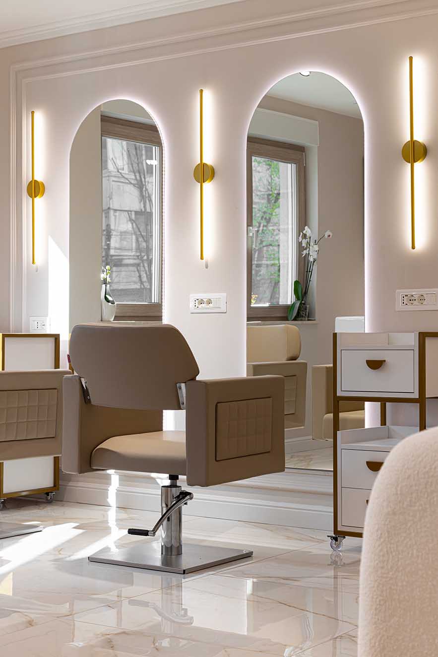 Refined salon interior featuring arched mirrors with integrated lighting, taupe styling chairs, and marble flooring. A sophisticated composition that appeals to interior designers drawn to symmetry, material harmony, and contemporary elegance.